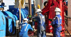 Workers operating machinery in industrial setting following ISO 9001 skills management